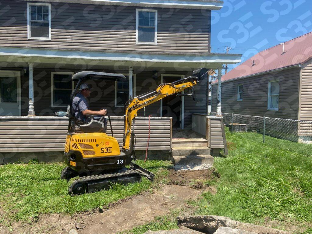 S3E mini excavator operating in front of a house