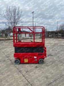 S3E red scissor lift on a concrete lot with bare trees and utility poles