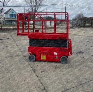S3E red scissor lift on a concrete lot with residential background