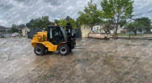 S3E yellow forklift on a wet concrete lot with trees and containers