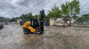 S3E yellow forklift on a wet concrete lot with trees and containers